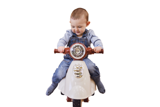 Happy baby boy rides a plastic children motorcycle in the playroom, isolated on a white background. A smiling child drives a moped toy, isolated on a white background. Kid age one year