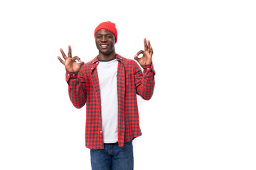 successful confident young american man in red cap and plaid shirt shows calm on white background with copy space