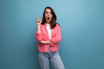 smart brunette lady casual style pointing finger at space for information on studio background