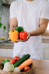 Male prepares cooking healthy food from fresh vegetables and fruits in kitchen room.