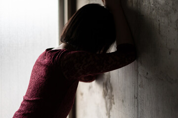 壁に手をつき悩む女性