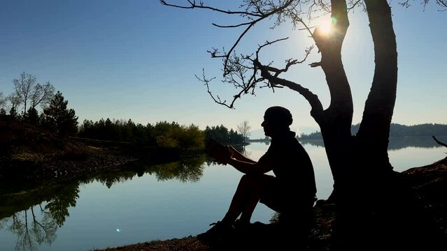 peaceful concept of person reading book in nature under tree