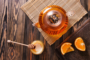 Citrus tea in teapot with honey and orange