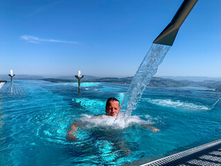 Man Enjoy Infinity Swimming Pool with Mountain and Lake Lucerne  View in a Sunny Day in Burgenstock, Nidwalden, Switzerland.