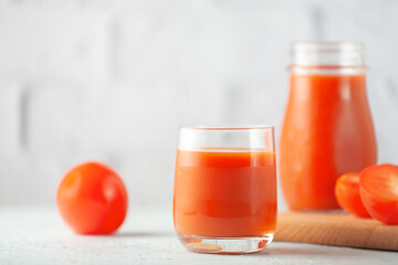 Glass of tomato juice with vegetables on white brick wall background