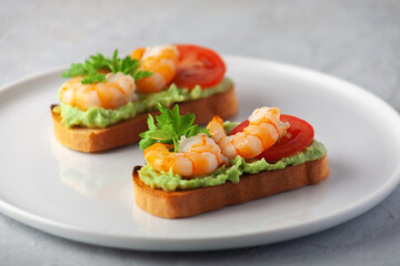 Healthy snack or shrimp bruschetta with avocado and bread. Fried shrimp and mashed avocado on toasted bread