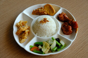 Nasi Campur or nasi rames. brown rice with sautéed vegetable, fried tempeh and tofu. fried fish and chicken soybeans. Indonesian food