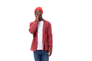 pensive smart dark-skinned man in a casual plaid shirt is talking on a white background with copy space