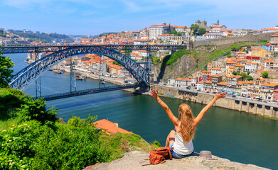 Woman touristwith arms raised enjoying beautiful panoramic view of famous iron bridge and old town- tour tourism in Portugal,  travel in Porto - obrazy, fototapety, plakaty