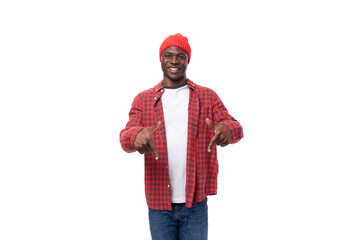 surprised positive young african man in cap and shirt telling news on isolated white background