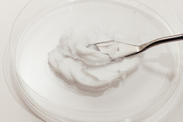 Smear Sample of White Face Moisturizing Cream in a Petri Dish at Laboratory on a White, close-up.