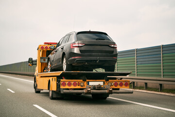 Tow truck with broken car on country road. Tow truck transporting car on the highway. Car service transportation concept.