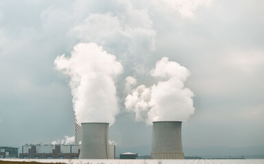 Twin nuclear power stacks rise above. A power plant in Europe.