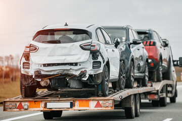 A heavily damaged cars on a trailer is being towed by a tow truck.