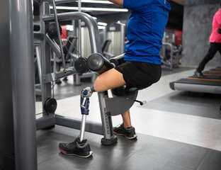 Low angle woman with prosthetic leg use exercise machine at fitness gym	