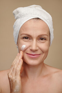 Face of middle-aged woman applying moisturizing lotion after evening shower