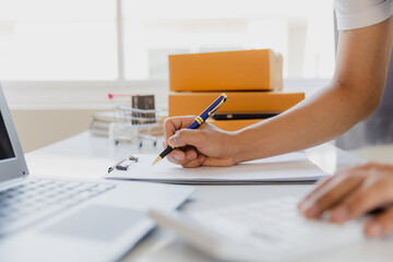 Fototapeta premium Asian Male SME Small Business Entrepreneur Working Freelance From Home Use smartphones and laptops for commercial inspections. online marketing Packaging Box SME Seller Concept Ecommerce Team online s