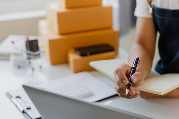 Asian Male SME Small Business Entrepreneur Working Freelance From Home Use smartphones and laptops for commercial inspections. online marketing Packaging Box SME Seller Concept Ecommerce Team online s