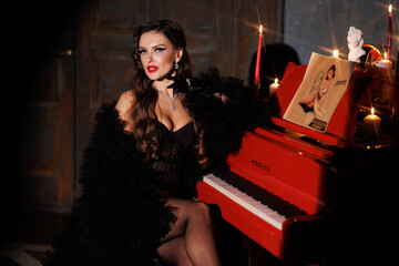 Fototapeta na wymiar Beautiful woman in retro style fashion black underwear and stockings, red lipstick, hairstyle. Red piano and round spot light, aperture. Girl portrait, porsh look, gloves