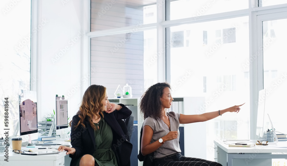 Poster open plan makes for open dialogue. two young businesswomen using a computer together in a modern off