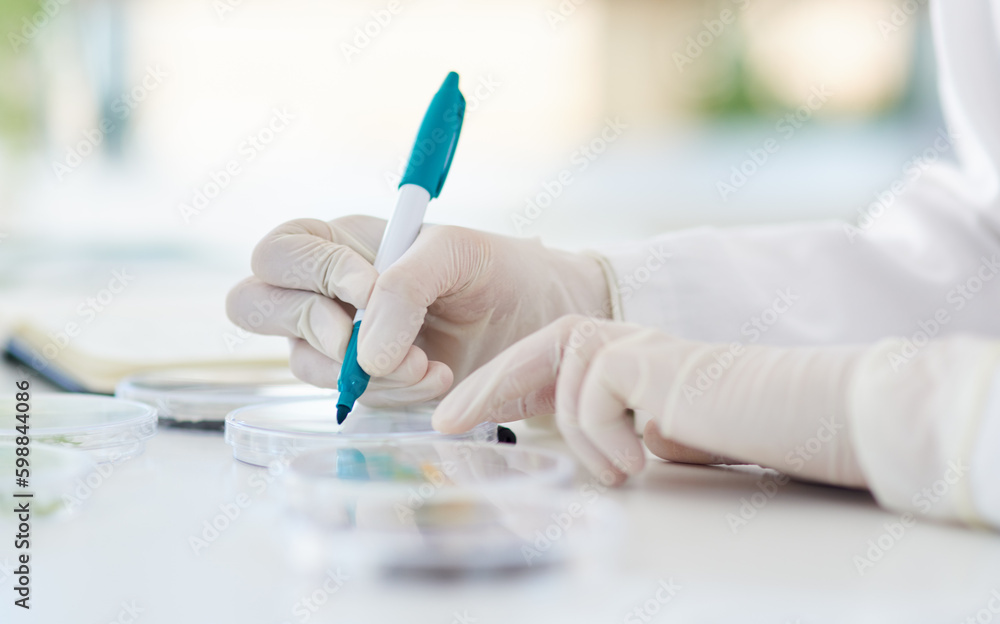 Poster marking each dish for easier identification. closeup shot of an unrecognisable scientist using a pen