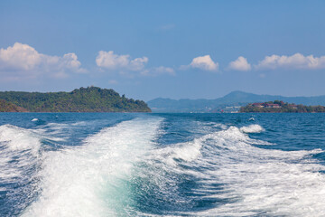 Waves from a speedboat on the blue sea with splashes and a trail from a boat or yacht. The concept of travel and voyage while on vacation in hot Asian countries.