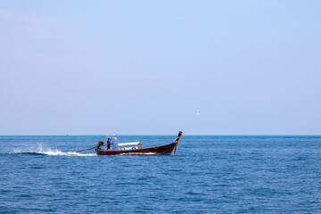 Obraz premium Old traditional Thai motorboat made of wood for fishing and transporting tourists on excursions in the Andaman Sea in clear turquoise water under a blue sky. Travel and vacation in phuket.