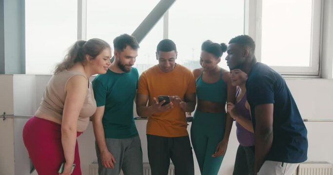 Hispanic man shows friends pictures from yoga class on phone