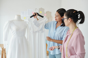 Young woman asking tailor to change bow on her wedding dress