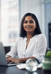 Success lies in the path of those who show dedication. Portrait of a young businesswoman working on a laptop in an office.