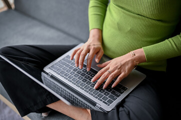 close-up image of a young Asian woman typing on keyboard, using her laptop