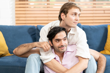 Gay Couple Sit Together on a Sofa at Home. Boyfriends are Hugging and Embracing Each Other. A gay...