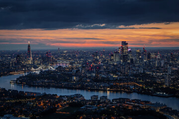 Fototapeta na wymiar Wide aerial panorama of the illuminated London skyline during evening, England, with River Thames leading into the city