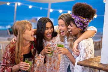 Four beautiful young women participate in a beach party at night, positive emotions of joy and happiness among best female friends, holiday concept and carefree