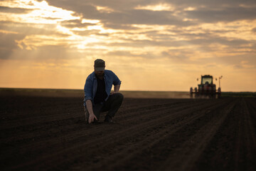  Satisfied tractor driver after work on agricultural field stands next to tractor.