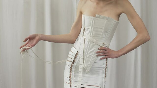 White corset styled for fashion editorial, slim woman model posing for photography photoshoot against white background