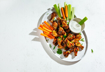 Buffalo chicken wings with vegetables and sauce. Food background with copy space. Top view