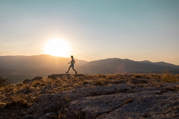 silhouette of a running man against the background of the sky and sunset in the mountains, sports and recreation.