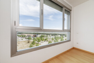 An empty room with a large window with unobstructed views of a park