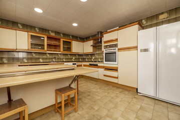 A spacious kitchen filled with cream cabinets with wood accents