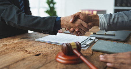 Businessman shaking hands with lawyer after discussing contract in courtroom Legal concept. Judge. Hammer of justice.