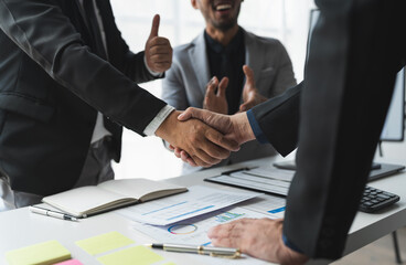 Team of businessmen, investors congratulate their teammates for successful performance in finance, stocks, marketing in a stand out with shaking hands in modern office.