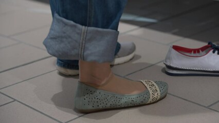 Closeup side view female foot in ballet flats on tiled floor indoors. Unrecognizable Caucasian adult woman trying on new shoes taking off footwear
