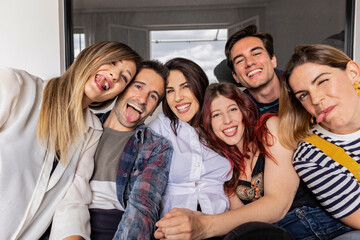 group of caucasian and hispanic friends young millennials, making selfie at home funny showing tongue grimace