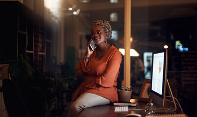 Making the time to chat to some international clients. a young businesswoman talking on a cellphone in an office at night.
