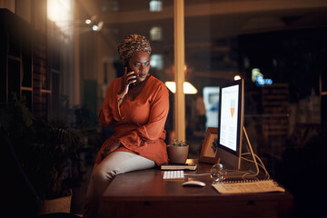 Is there a problem. a young businesswoman talking on a cellphone in an office at night.