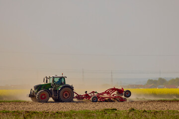 Fototapeta premium a tractor in an agricultural field shredding the earth on a hot day