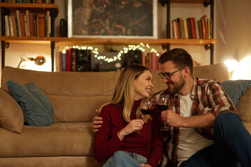 Romantic young couple relaxing at home and drinking red wine