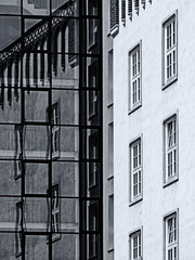 Schwarz-weiße Aufnahme des Kontrastes  alter und moderner Architektur mit Spiegelung