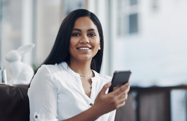 Fototapeta premium My connections are always close by. Portrait of a young businesswoman using a cellphone in an office.